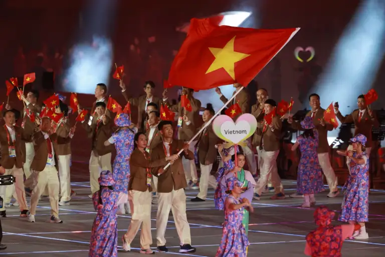 Đinh Quang Kiệt và Lê Thanh Thuý vẫy quốc kỳ trong lễ diễu hành tại lễ khai mạc ASIAD 2026 trên sân vận động Paloma Mizuho, Nagoya, ngày 19/9/2026. Ảnh: AFP
