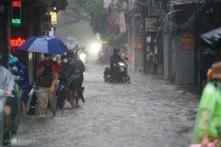 Mưa lớn trên phố Phùng Khoang, người dân phải dắt xe vào hai bên lề đường tránh ngập. Ảnh: Hoàng Giang
