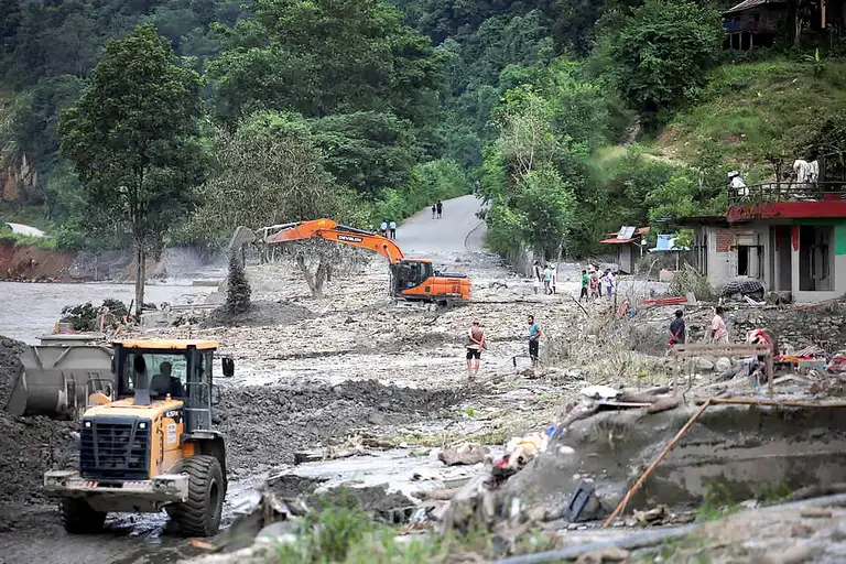 Một máy xúc đang sửa chữa đoạn đường bị hư hại ở Nepal, gần sông Trishuli, ngày 7-9 - Ảnh: REUTERS