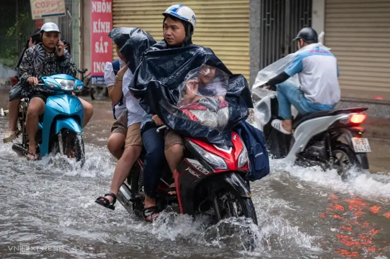 Phụ huynh chở con đi làm trong mưa ngập trên đường Mỹ Đình. Ảnh: Thế Bằng