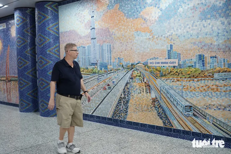 Du khách nước ngoài ngoái đầu chiêm ngưỡng bức tranh đoàn tàu metro băng qua sông Sài Gòn với Landmark 81 phía sau (Metro thành phố Hồ Chí Minh ngày mới) - Ảnh: HỮU DUY