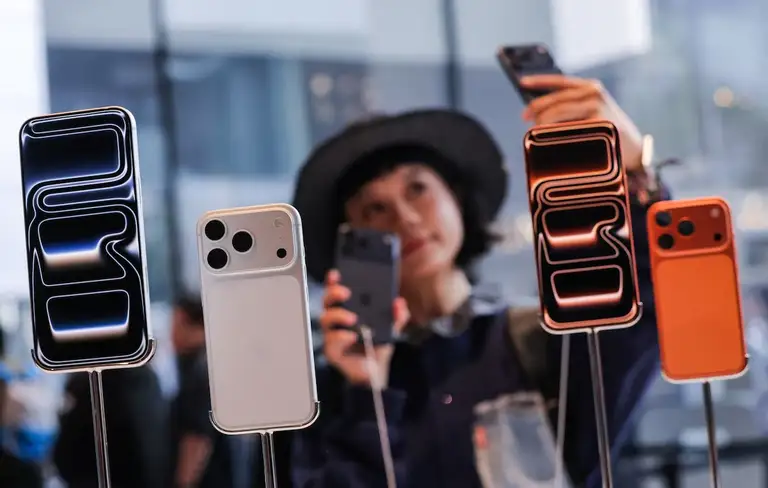Một phụ nữ chụp ảnh selfie với những chiếc iPhone bên trong cửa hàng Apple tại Bắc Kinh (Trung Quốc) - Ảnh: REUTERS