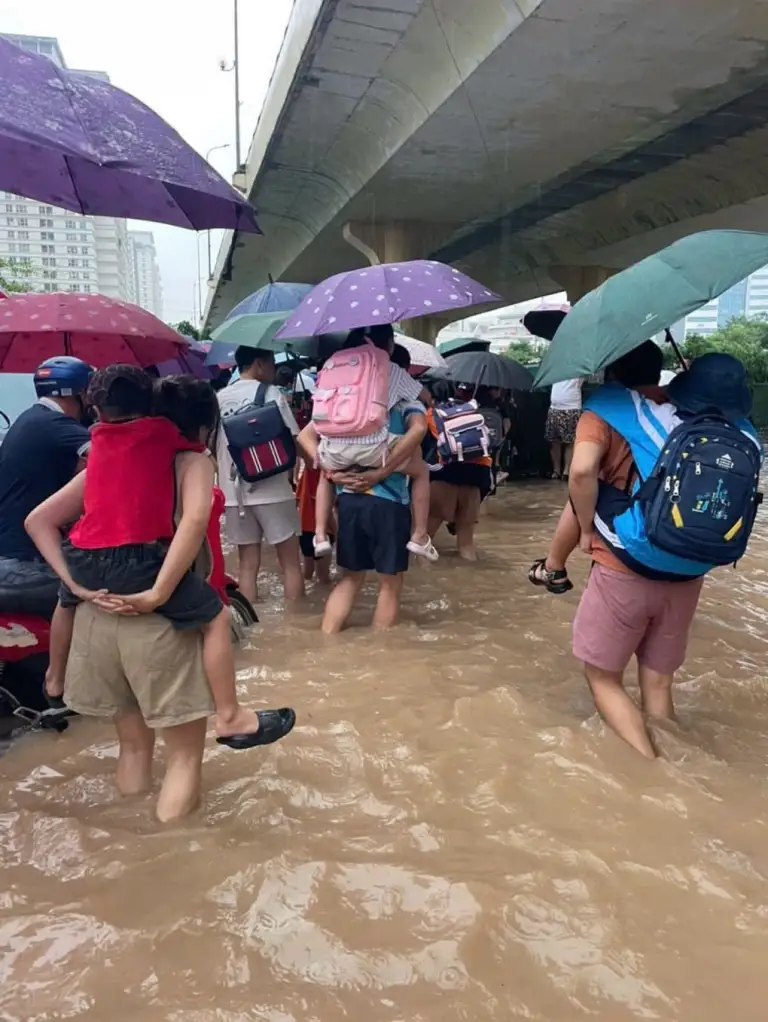 Cư dân chung cư Xuân Mai Complex lội nước cõng con đi học, sáng 17/9. Ảnh: Cư dân cung cấp