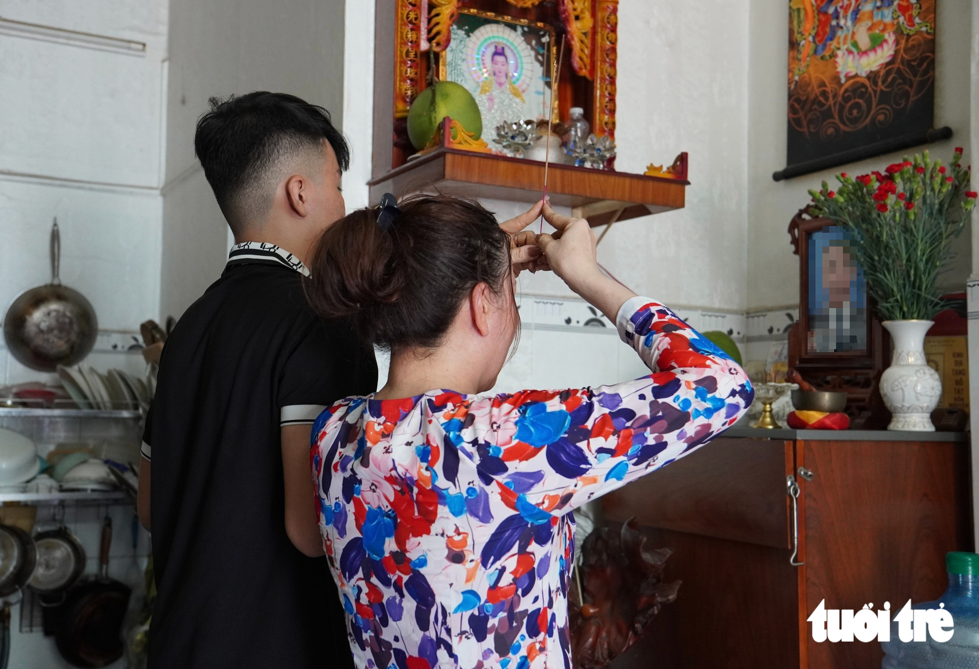Chị Nguyễn Thị Lệ Hiền và con trai Nguyễn Đăng Khoa thắp nén hương tưởng nhớ người chồng, người cha đã mất vì COVID-19 vào năm 2021. Sau biến cố, chị Hiền nghỉ nghề giáo mà chị đã theo 20 năm, chấp nhận bắt đầu lại từ đầu bằng công việc bán cà phê vỉa hè, làm bánh bột lọc... để có thời gian nuôi con - Ảnh: XUÂN MAI