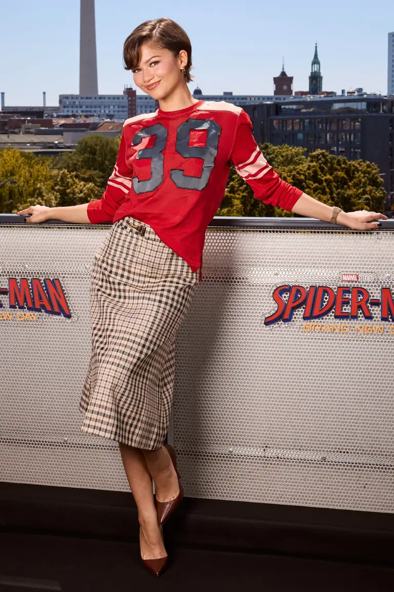 Tại Berlin, Zendaya mang đến một màn biến hóa thú vị khi lấy cảm hứng từ không khí của World Cup. Nữ diễn viên diện chiếc áo đấu màu đỏ của Coach, chân váy họa tiết kẻ ô và đôi giày cao gót mũi nhọn màu nâu - Ảnh: Sebastian