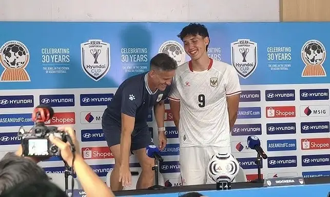 HLV John Herdman đứng lên ghế cạnh tiền đạo Mitchell Baker trong họp báo sau trận Indonesia thắng Campuchia 5-1 trên sân Pakansari, thành phố Bogor, Indonesia tối 27/7/2026. Ảnh: chụp màn hình