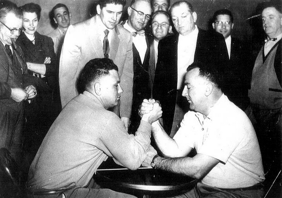 Oliver Kullberg (bên trái) và Jack Homel (bên phải) tranh tài trong trận vật tay đầu tiên tại Gilardi’s Corner, dưới sự theo dõi của Soberanes (đứng sau Kullberg) và Mike Gilardi (đứng sau Homel).