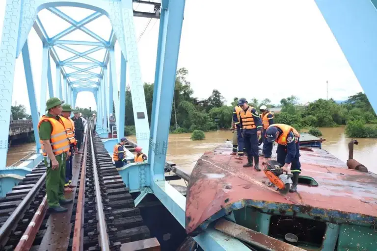 Cảnh sát chữa cháy cắt nóc cabin sà lan mắc kẹt vào cầu đường sắt Mỹ Chánh. Ảnh: Khôi Trần