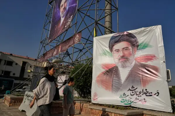 Người dân đi ngang các biểu ngữ in chân dung Lãnh tụ tối cao Mojtaba Khamenei ở Tehran ngày 29-6 - Ảnh: AP