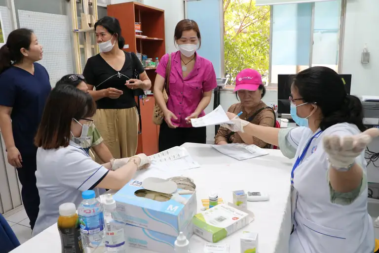 Nhân viên trạm y tế hướng dẫn người dân thăm khám sức khỏe định kỳ - Ảnh: THU HIẾN