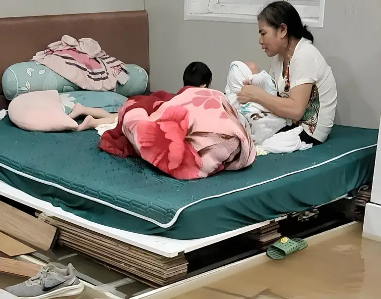 Mẹ anh Bền bế cháu trên chiếc giường ngấp nghé nước dù đã được kê cao, chiều 17/9. Ảnh: Nhân vật cung cấp