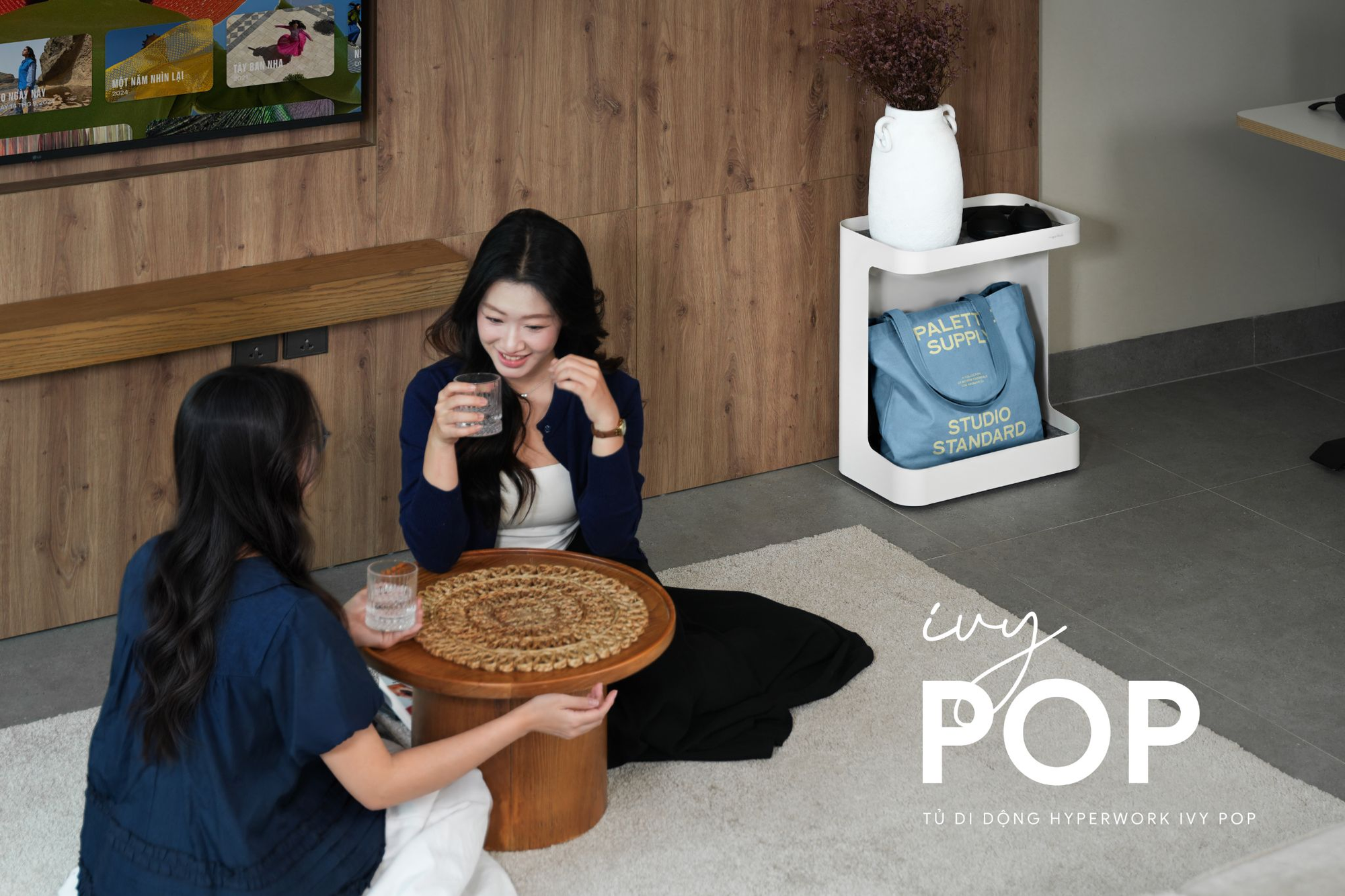Tủ Ivy Pop 2 tầng đặt cạnh bàn làm việc, tầng trên có sổ và ly nước, tầng dưới có balo