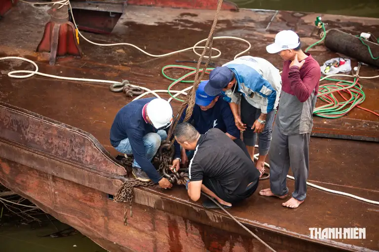 Các thành viên trong đội trục vớt tàu móc cần cẩu vào thân sà lan