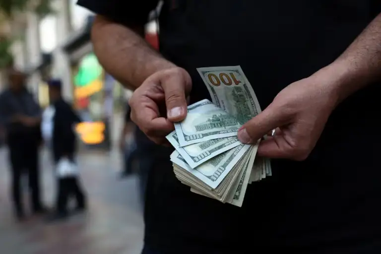 Một người buôn ngoại tệ đếm những tờ tiền mệnh giá 100 USD tại Tehran, Iran, ngày 2/5. Ảnh: Reuters