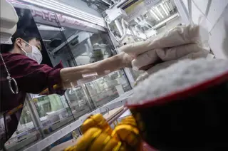 Một nhân viên bổ sung các túi gạo vào máy gắp quà tại trung tâm giải trí Benex - Ảnh: AFP