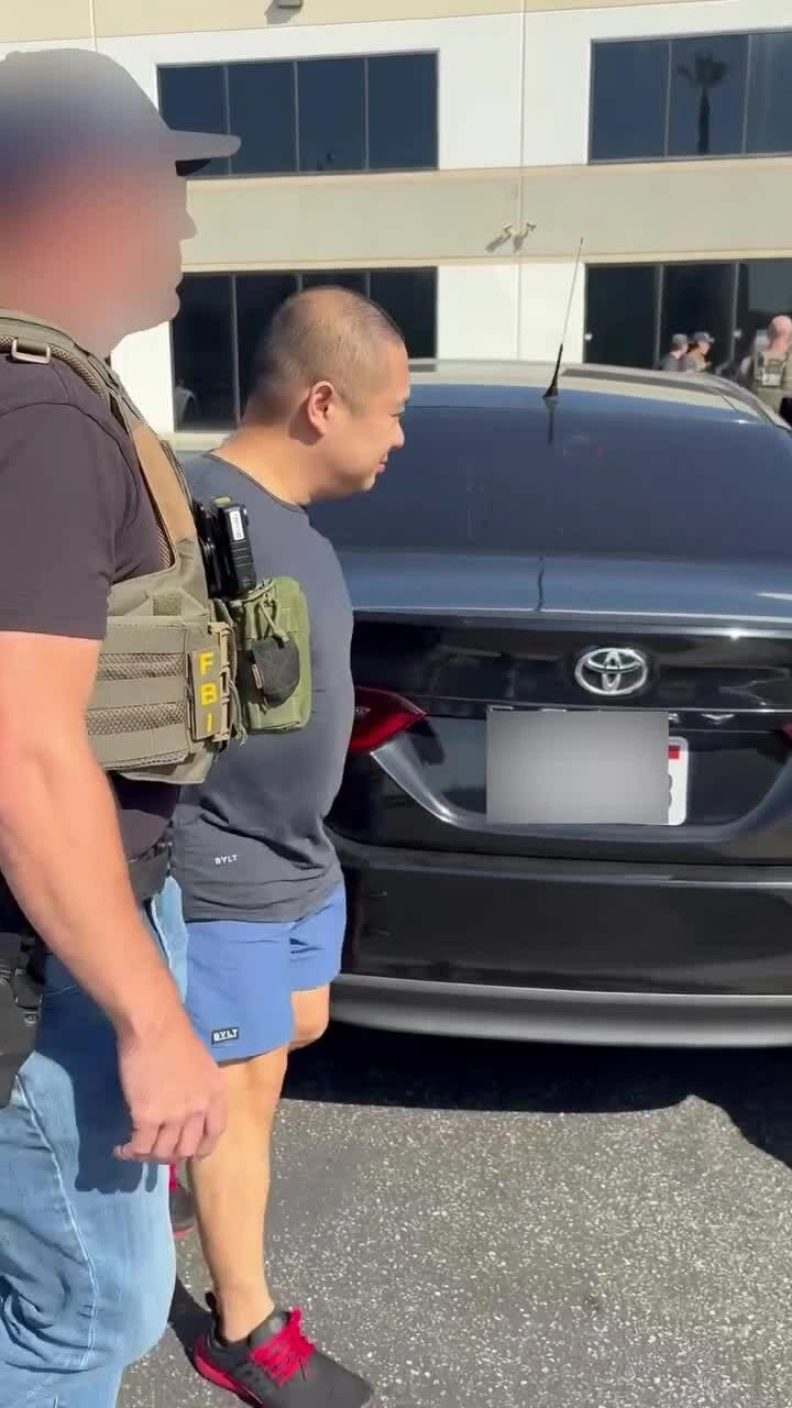 Đặc vụ FBI áp giải Greg Lui lên xe bên ngoài công ty Earthmade. Video: Facebook/ California Post