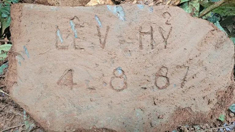 Mảnh bia mộ ghi thông tin "Lê V. HỶ - 4.8.67"