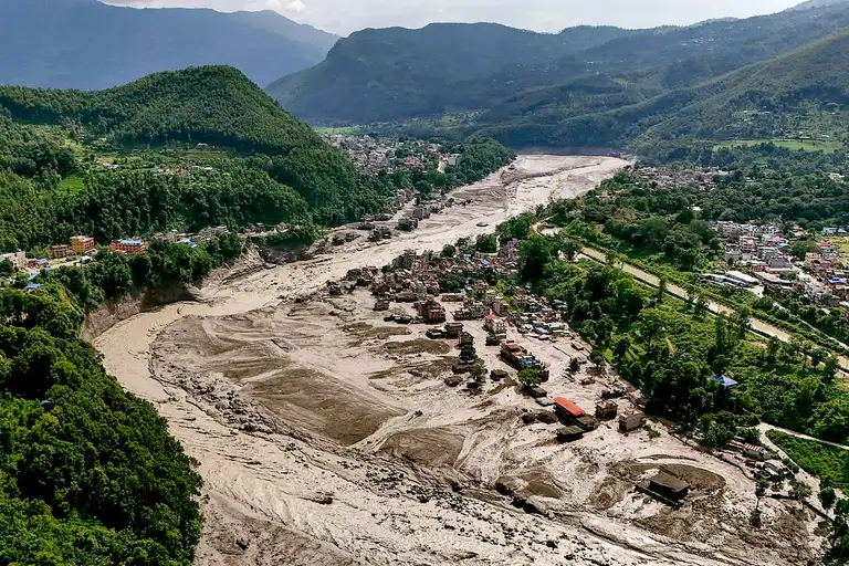 Nhà cửa của người dân huyện Nuwakot, Nepal, bị hư hại do lũ quét nằm chênh vênh bên bờ sông - Ảnh: VCG