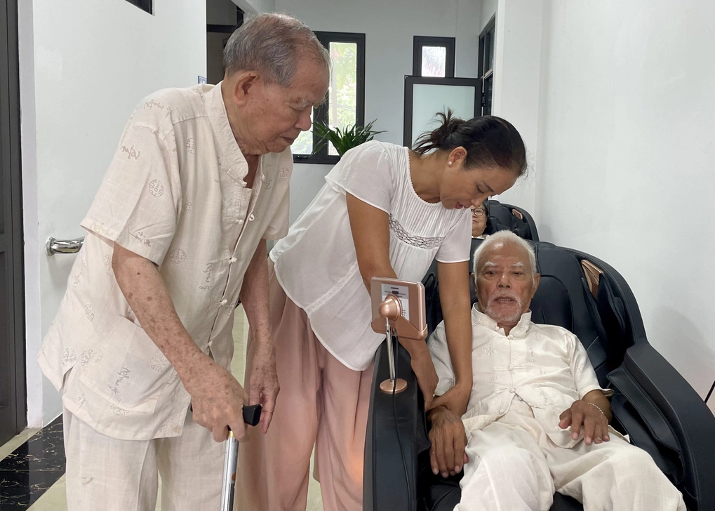Chị Mai Hương hỗ trợ bố nằm máy massage tại Cơ sở chăm sóc người cao tuổi phường Tây Hồ, hôm 1/10. Ảnh: Phan Dương