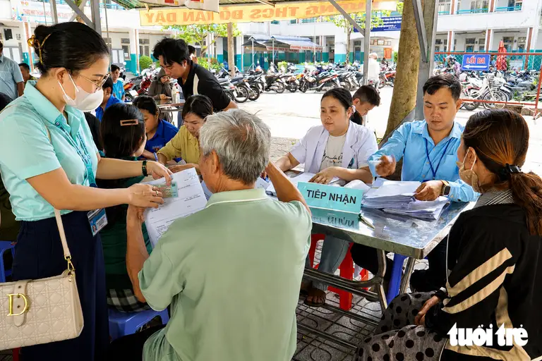 Bệnh viện Đa khoa khu vực Hóc Môn cùng chính quyền địa phương hỗ trợ người dân khâu tiếp nhận, sàng lọc trước khi được khám sức khỏe miễn phí - Ảnh: XUÂN MAI