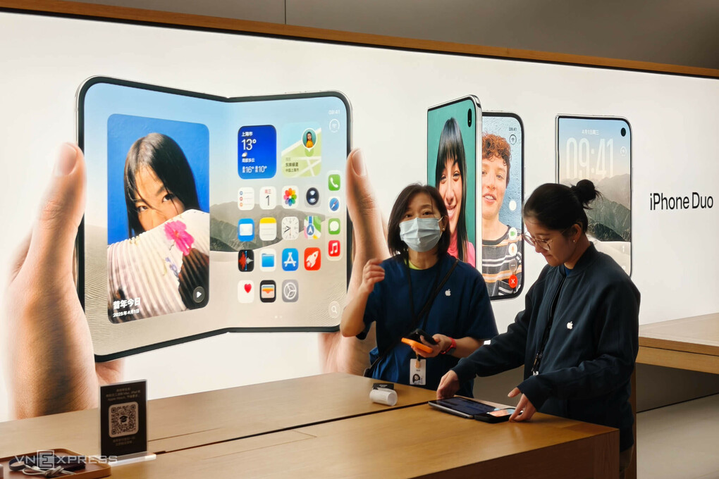 Nhân viên Apple Store Thượng Hải bên bảng quảng cáo về điện thoại màn hình gập iPhone Duo. Ảnh: Trọng Đạt