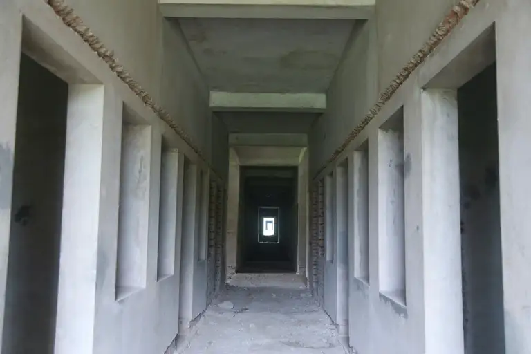 Một dãy phòng đã được trát vữa nhưng vẫn trong tình trạng bỏ dở. Nhiều mảng tường bên trong công trình vẫn để nguyên phần gạch xây, cho thấy quá trình hoàn thiện đã dừng lại từ nhiều năm trước.