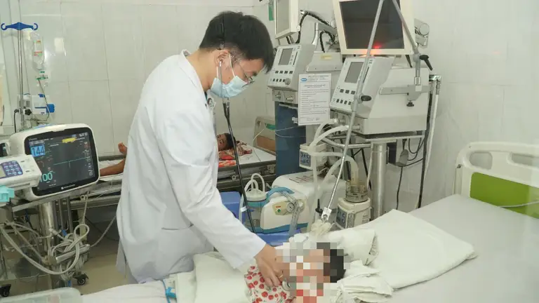 Bác sĩ Nguyễn Văn Chiến khám cho bé gái 3 tháng tuổi sau khi gắp đinh vít - Ảnh: QUANG NHẬT