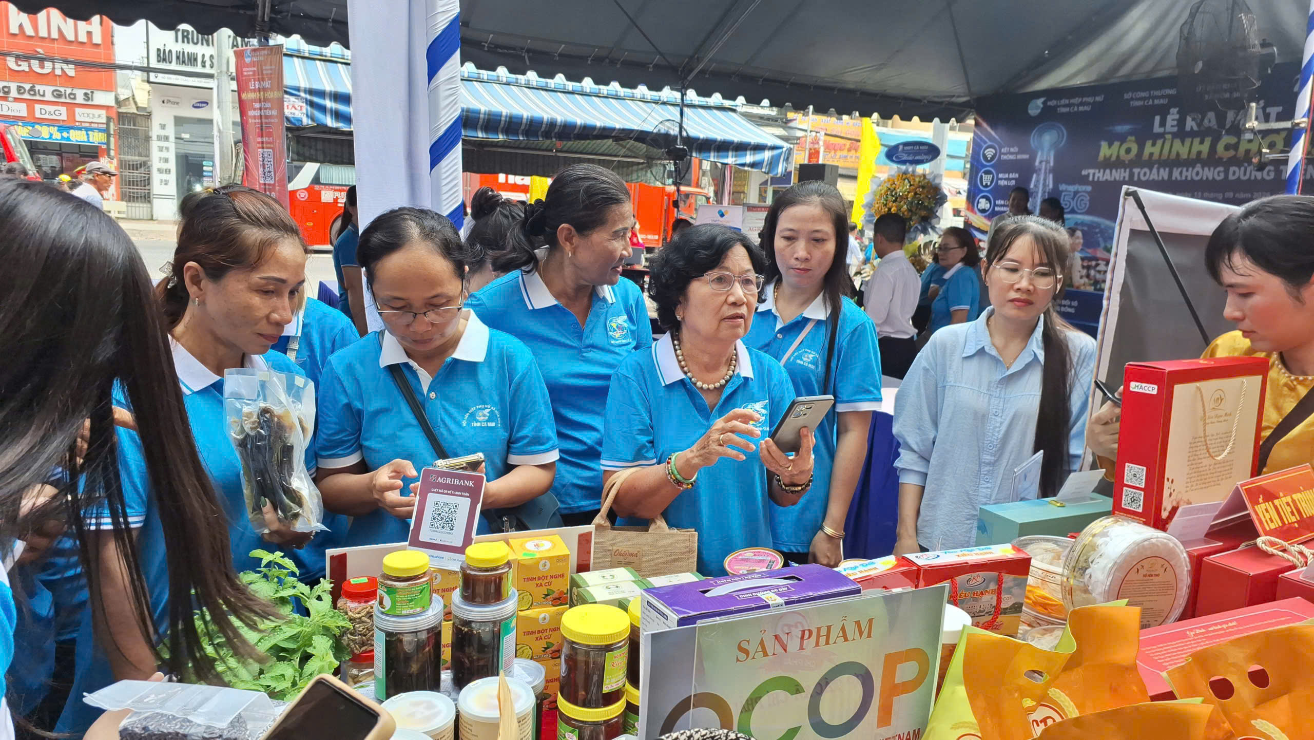 Người dân trải nghiệm thanh toán bằng mã QR tại gian hàng sản phẩm OCOP trong lễ ra mắt mô hình chợ thanh toán không dùng tiền mặt ở Cà Mau
