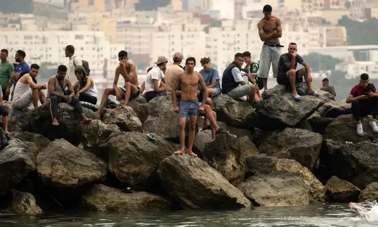 Người di cư ngồi trên các mỏm đá sau khi bơi qua vùng biển gần biên giới Morocco để vào Ceuta, lãnh thổ tự trị của Tây Ban Nha ở Bắc Phi, hôm 31/7. Ảnh: AFP
