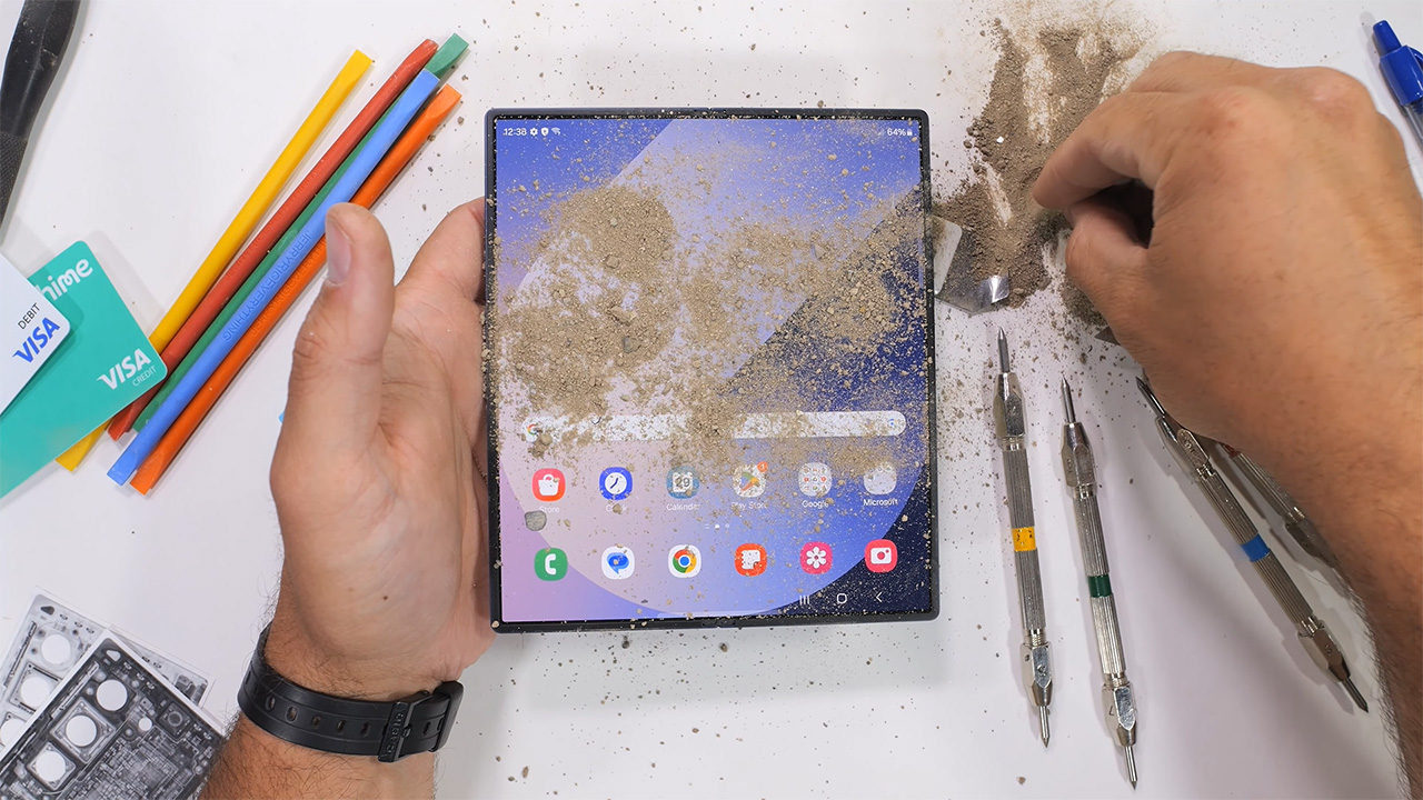 Cát và sạn được đổ trực tiếp lên màn hình trong của Galaxy Z Fold8 trong bài kiểm tra của JerryRigEverything. Ảnh chụp từ video của kênh.