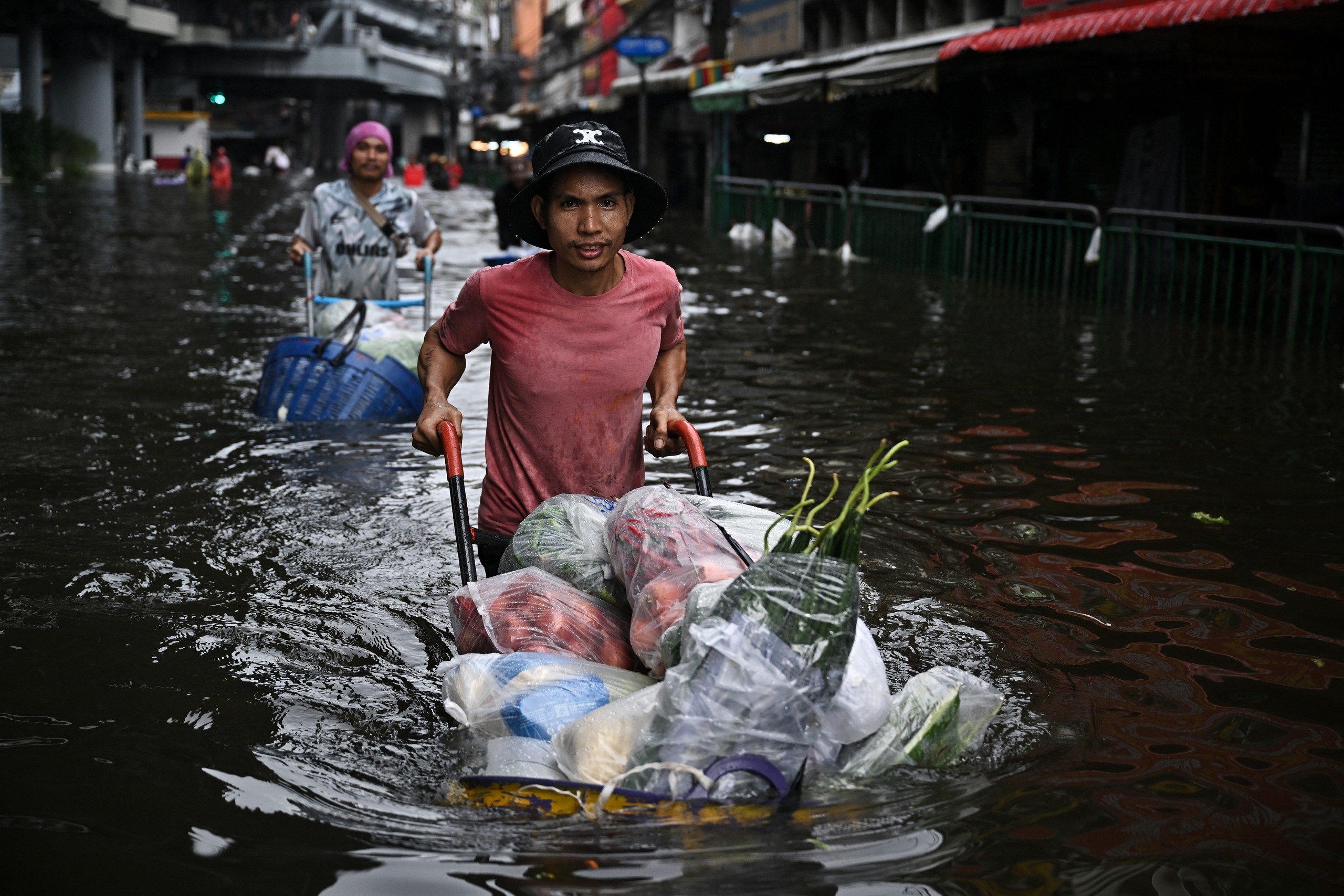 Các tiểu thương vận chuyển hàng hóa qua khu vực ngập nước ở quận Bang Kapi, Bangkok ngày 28-9 - Ảnh: AFP