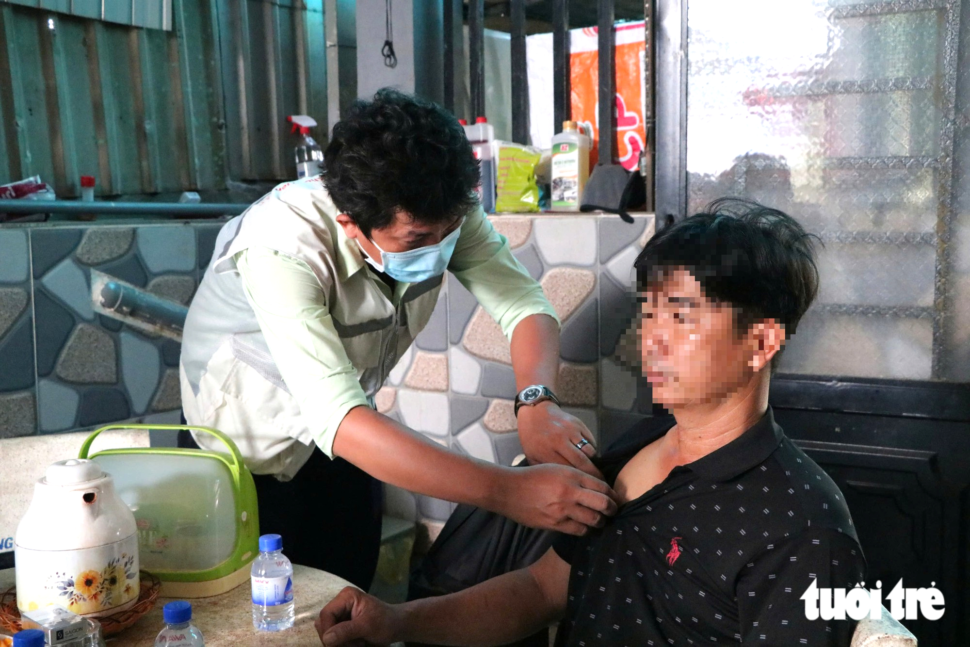 Nhân viên y tế nhẹ nhàng kiểm tra thân nhiệt, hỏi thăm tình trạng sức khỏe của từng người trong gia đình có ca bệnh tử vong do não mô cầu - Ảnh: THU HIẾN